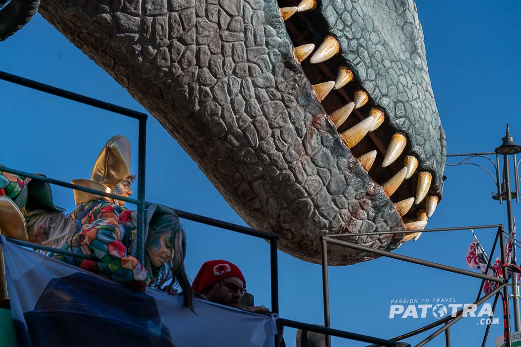 Mensch auf dem Karnevalswagen unter einem riesigen Dinosauriermaul