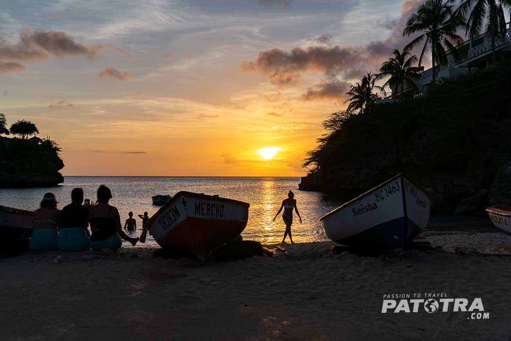 Mehrere Personen betrachten den Sonnenuntergang am Strand von Playa Lagun, Curacao
